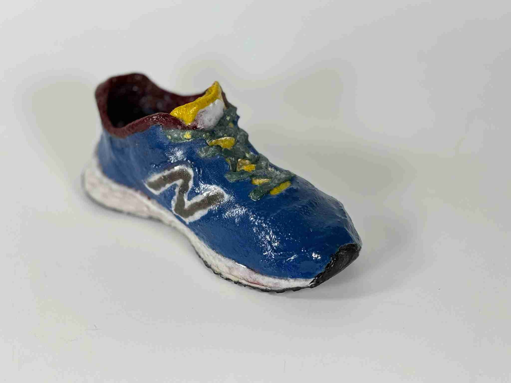 Blue sneaker with yellow tongue, green laces and red trim made of glass