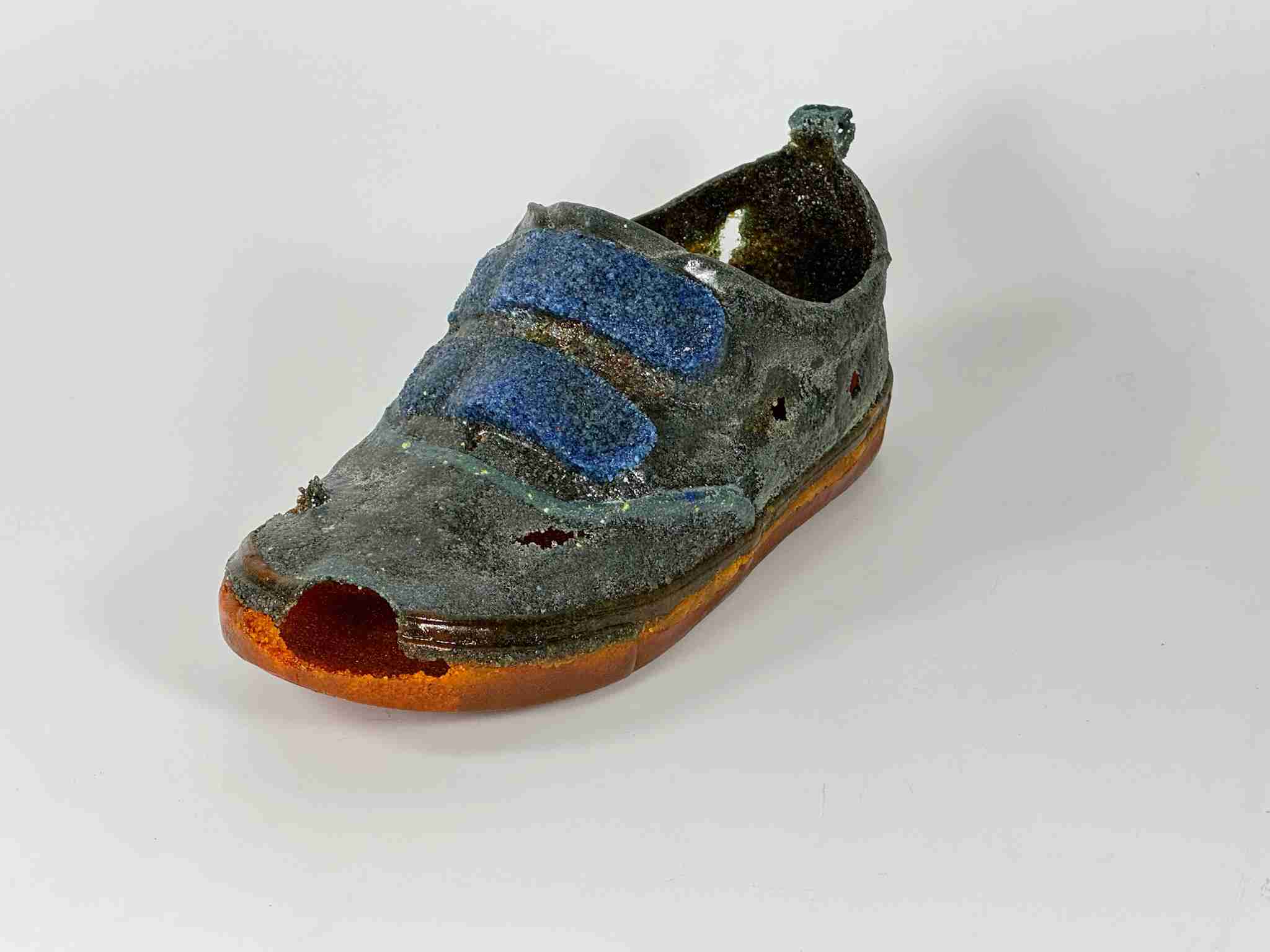 blue sneaker with orange sole and lots of holes