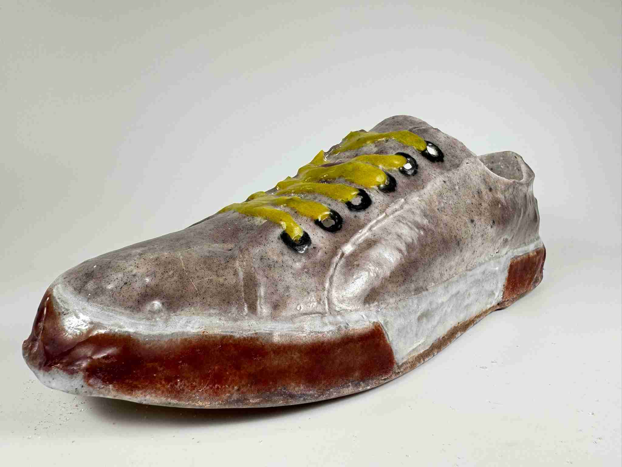 Glass shoe with tan uppers, black eyelets, yellow laces and red and white rubber