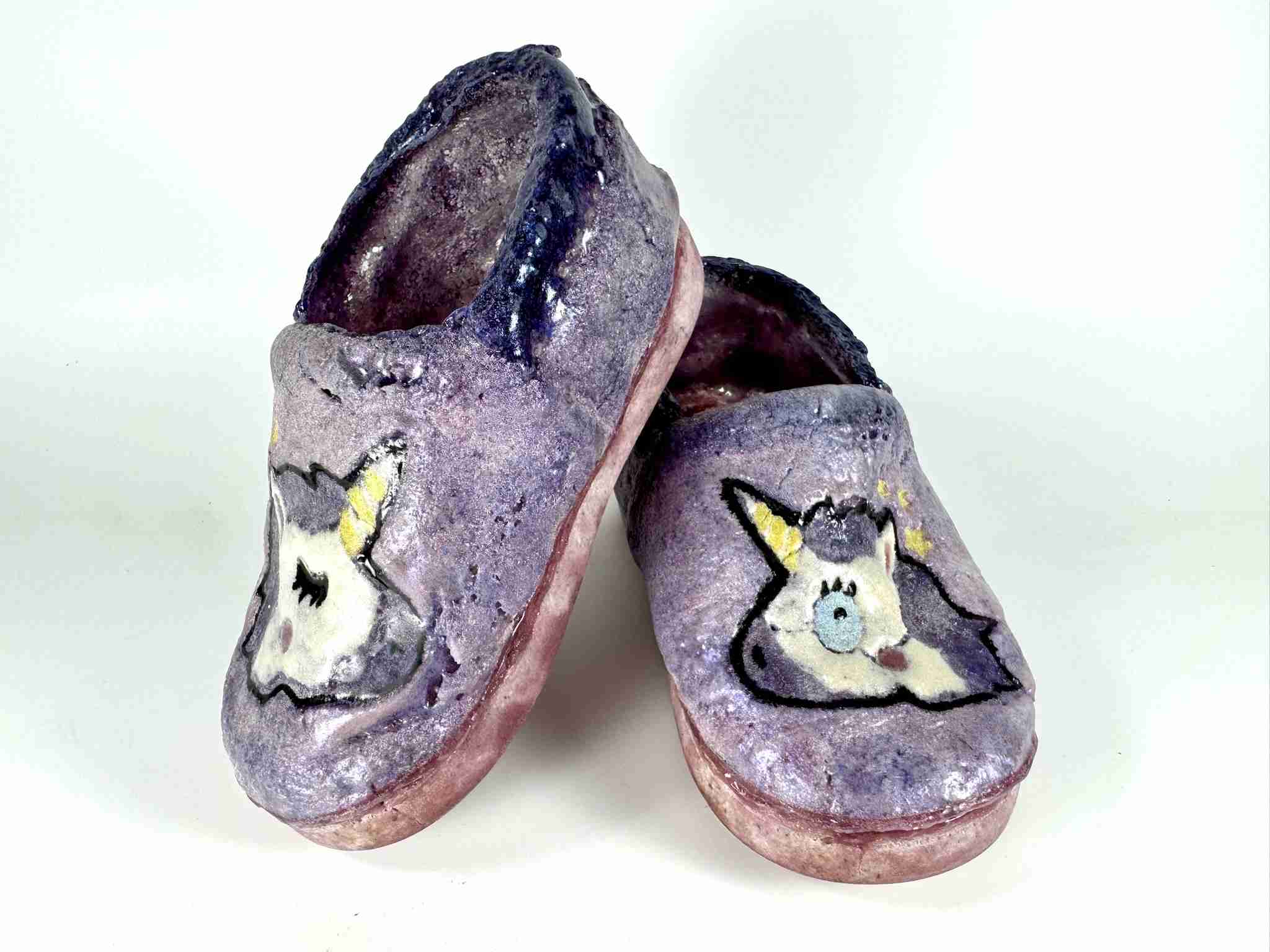 Two glass slippers in purple with unicorn heads on the toe box.