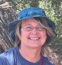 Woman wearing a bucket hat and glasses with a big smile
