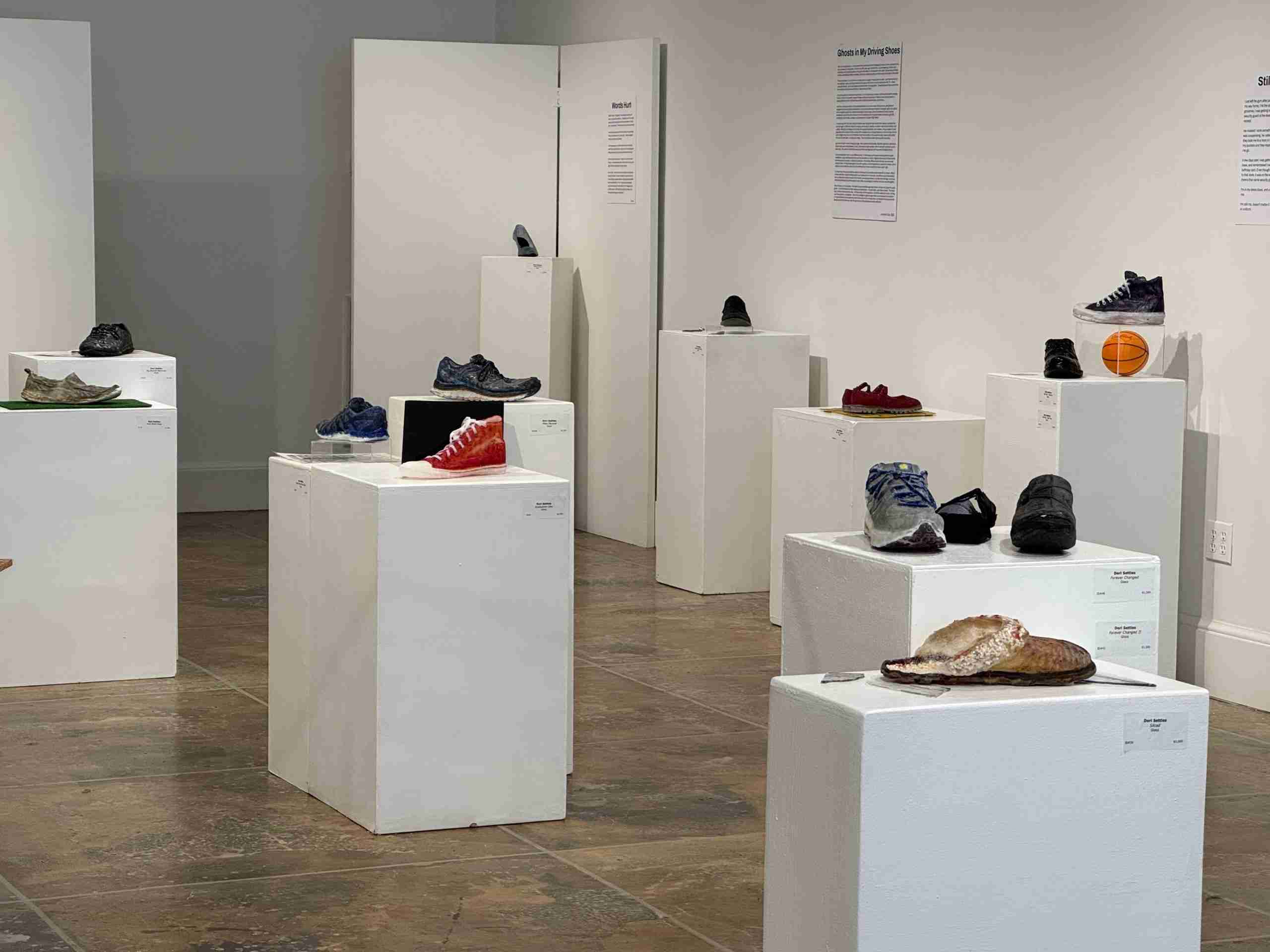 Gallery display of multiple shoes on white pedestals