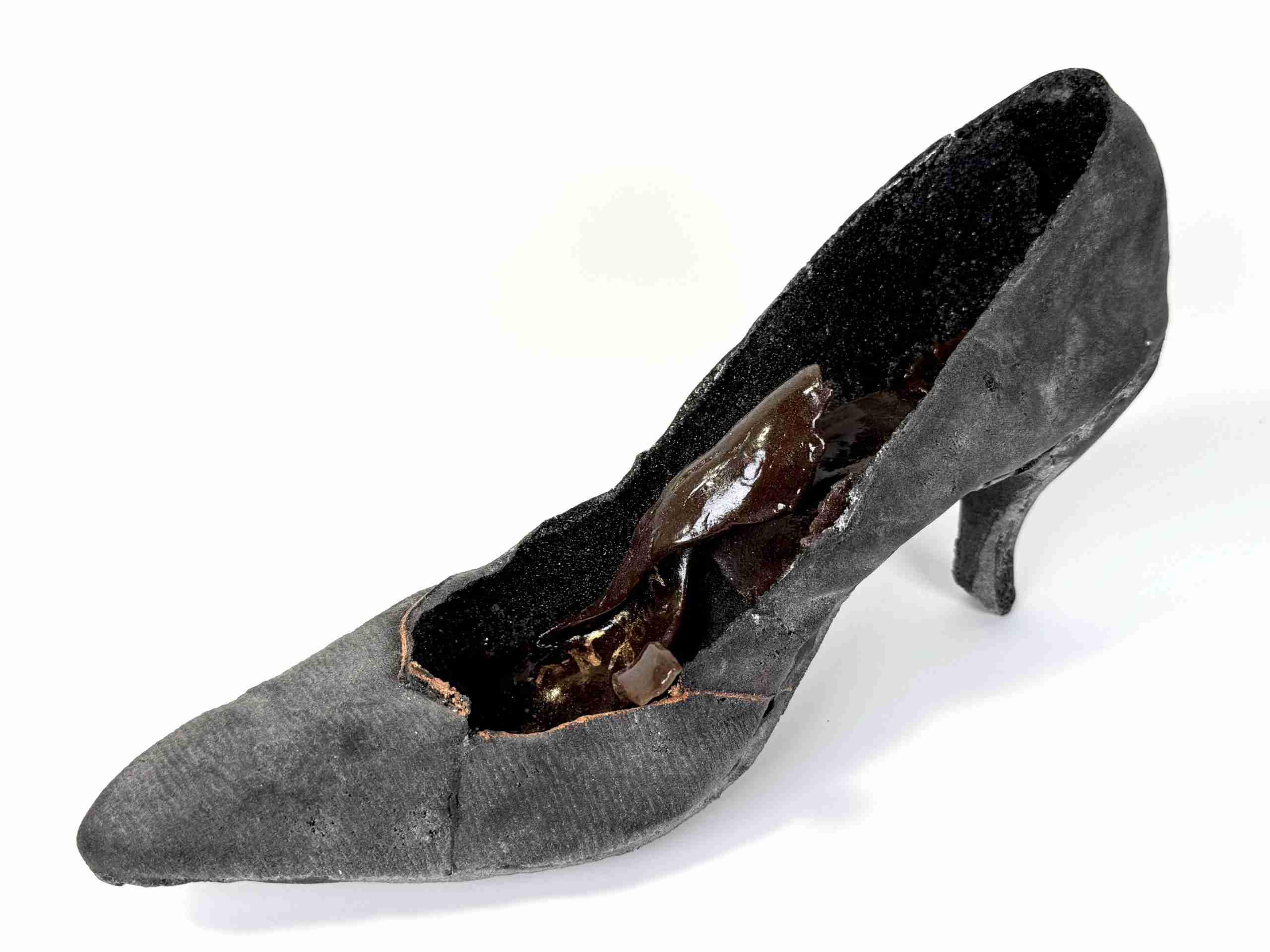 Glass shoe made in black with a brown insole, appears to be falling apart, created by Dori Settles