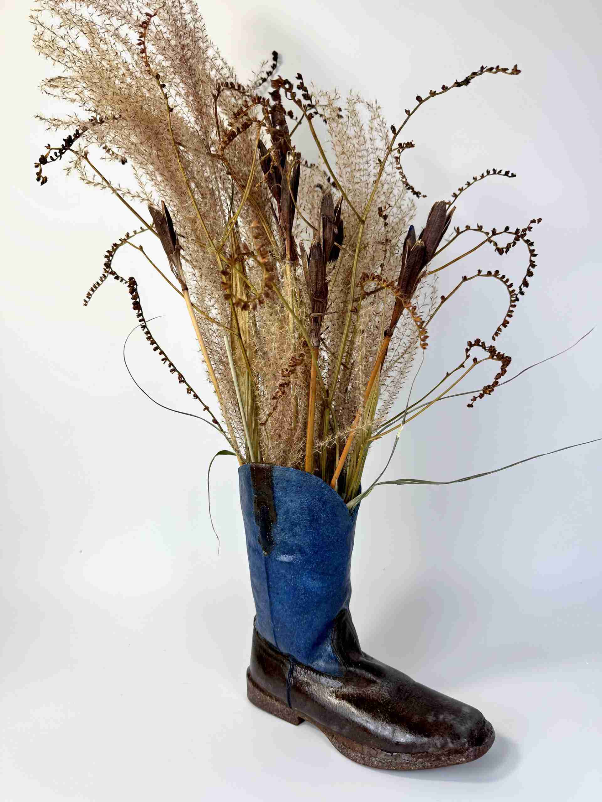 Glass Blue and Brown Cowboy boot with dried grasses set inside like a vase created by Dori Settles